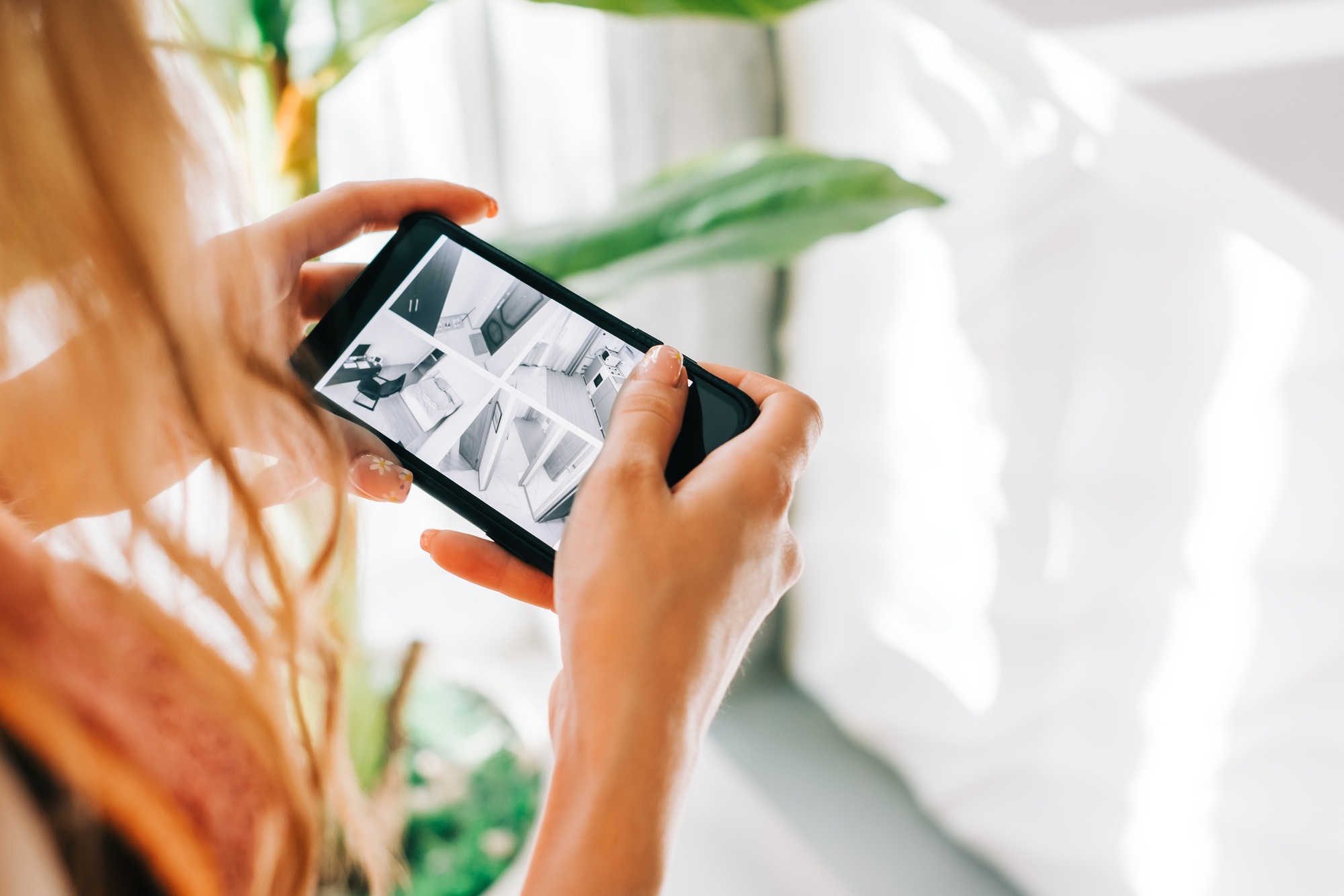 Caucasian woman monitoring security cameras on smartphone indoors, closeup.