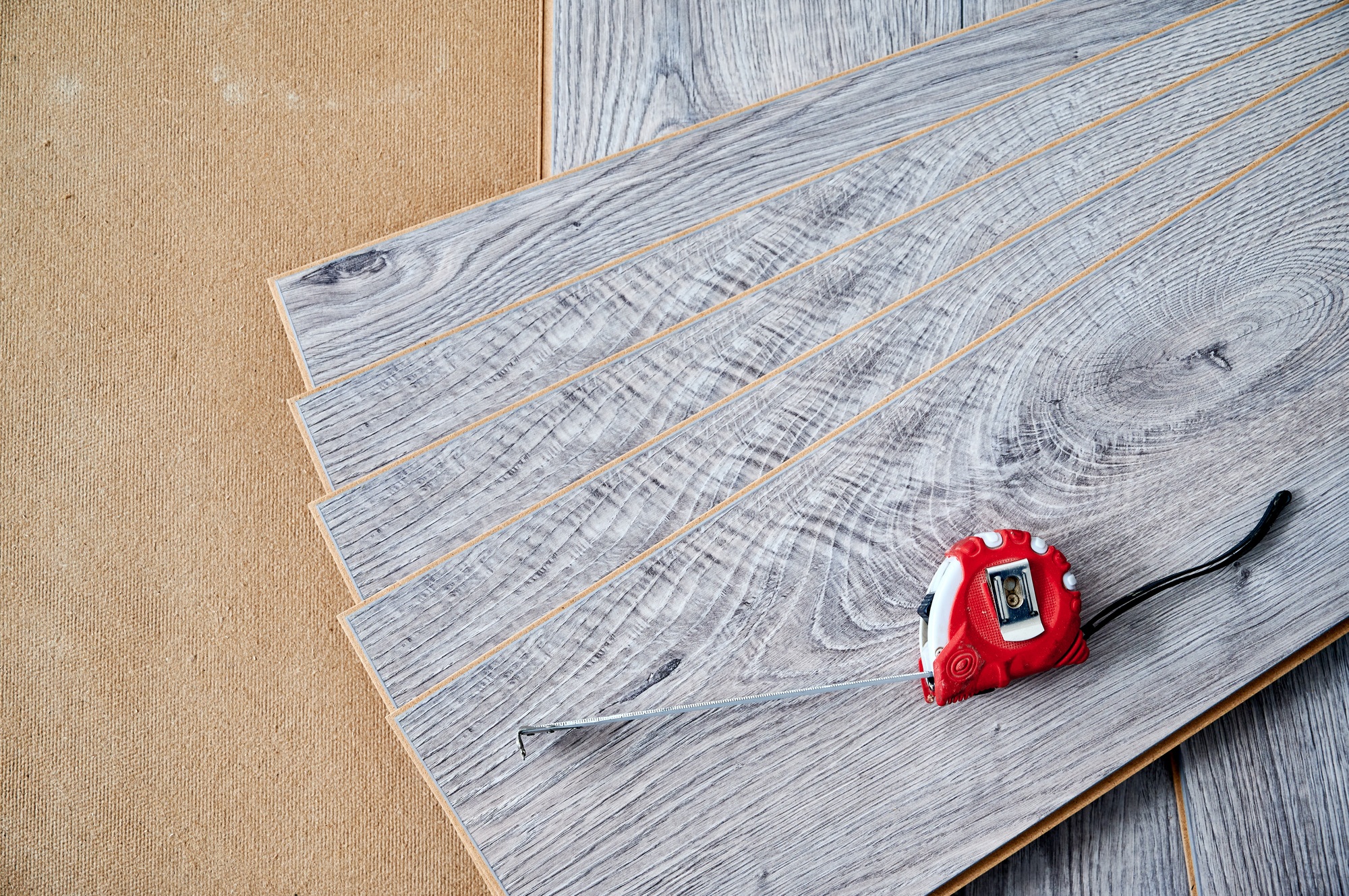 Laminate wood planks with tape measure on the floor.