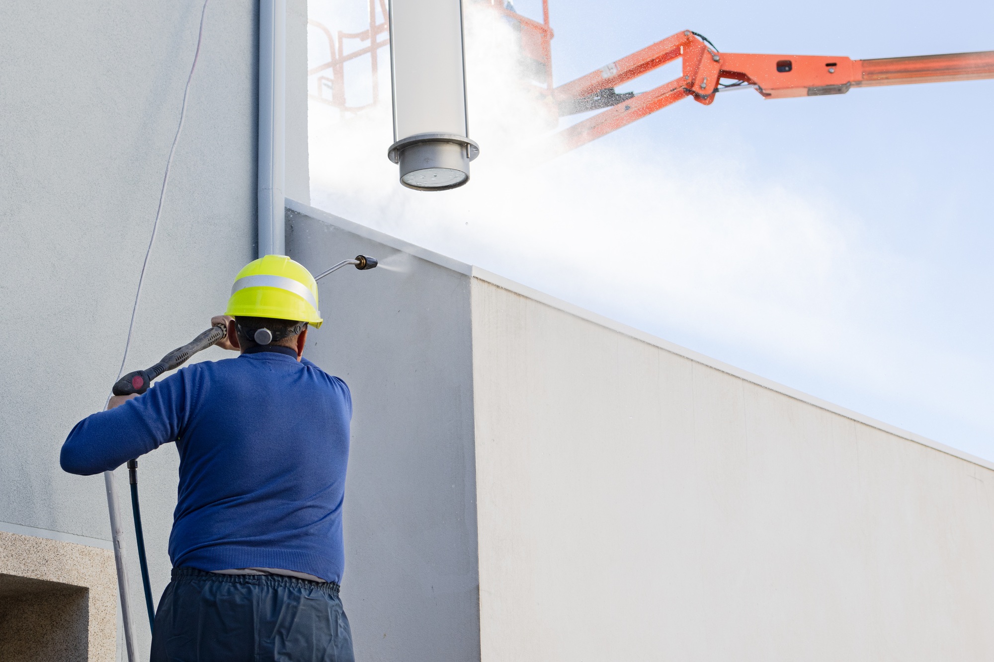 Worker cleaning a building facade with high pressure water jet